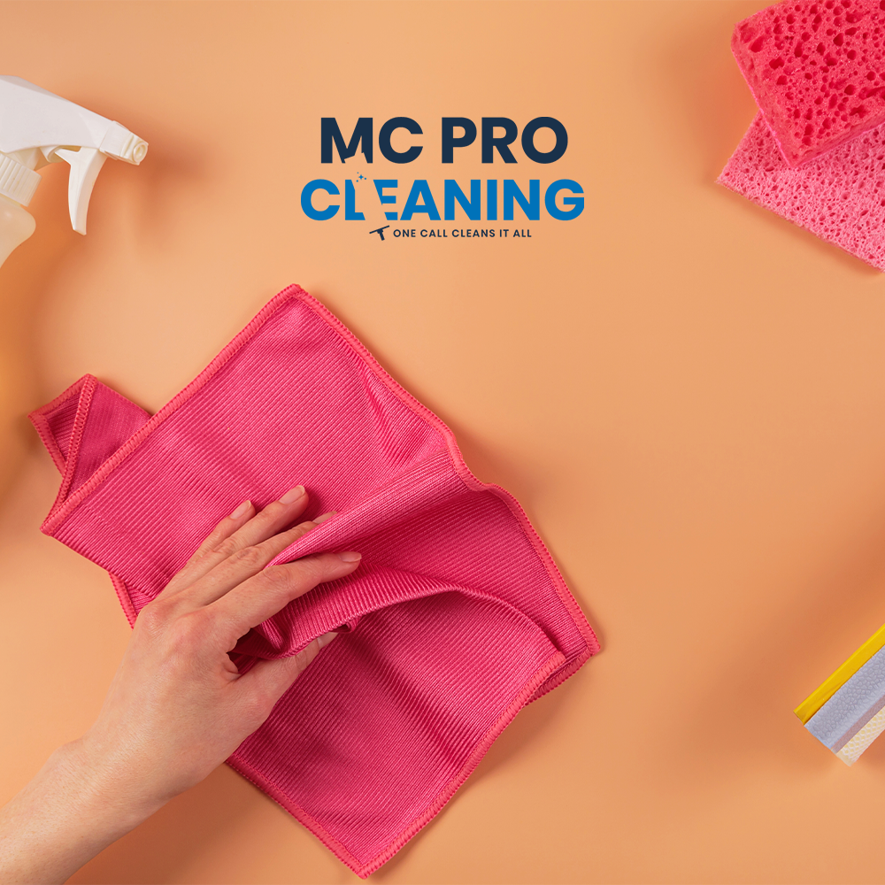 Flat lay of pink cleaning gloves and microfiber cloths on peach background, branded with MC Pro Cleaning